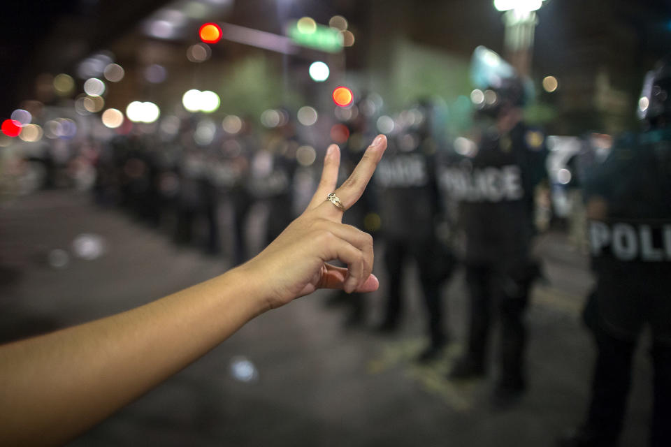 A woman makes a peace sign before a line of police preparing to advance upon demonstrators after a Trump rally at the Phoenix Convention Center on Aug. 22, 2017, in Phoenix.