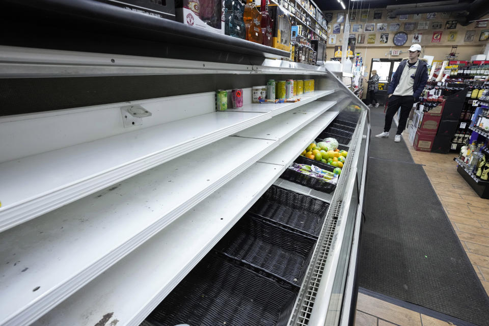 A customer views an empty refrigerated section at Mr. C's Deli in Grosse Pointe Farms, Mich., Friday, Feb. 24, 2023. The store was using a generator for power. Michigan is shivering through extended power outages caused by one of the worst ice storms in decades. (AP Photo/Paul Sancya)