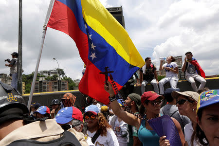 A woman holds up a crucifix during a women's march to protest against President Nicolas Maduro's government in Caracas, Venezuela, May 6, 2017. REUTERS/Marco Bello