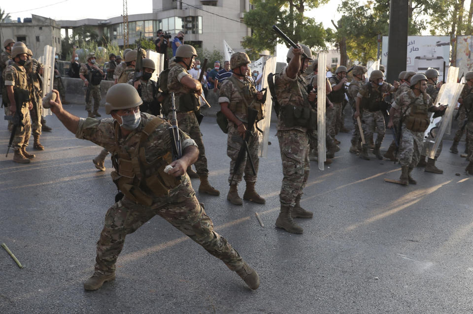 A Lebanese army soldier throws stones against the anti-government protesters, during a protest against the Lebanese President Michel Aoun near the presidential palace, in Baabda east of Beirut, Lebanon, Saturday, Sept. 12, 2020. Soldiers fired rubber bullets and live rounds in the air to disperse hundreds of protesters trying to march to the presidential palace during an anti-government demonstration. (AP Photo/Bilal Hussein)