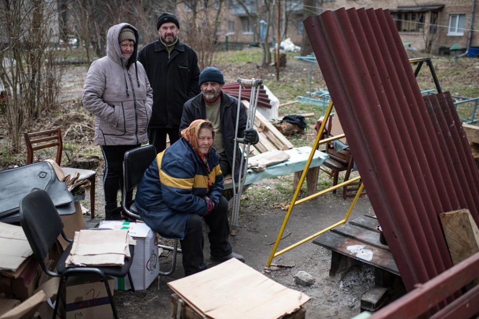 Residents sit by a makeshift stove next to their apartment building in Bucha, Ukraine. The Ukrainian government has accused Russian forces of committing a 