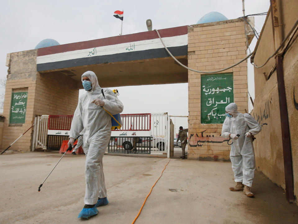 Workers in protective suits spray disinfectants near the gate of Shalamcha Border Crossing, after Iraq shut a border crossing to travellers between Iraq and Iran, Iraq March 8, 2020. REUTERS/Essam al-Sudani