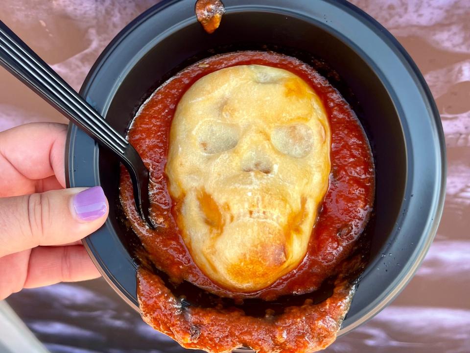 hand holding bowl with skull-shaped pizza from halloween horror nights