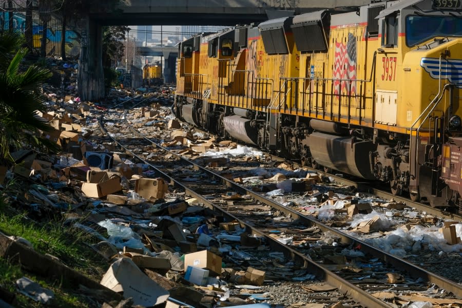FILE – A train passes by as shredded boxes and packages at a section of the Union Pacific train tracks in downtown Los Angeles on Jan. 14, 2022. Authorities say dozens of handguns and shotguns were among items stolen by thieves who raided cargo containers aboard trains near downtown Los Angeles for months. (AP Photo/Ringo H.W. Chiu)