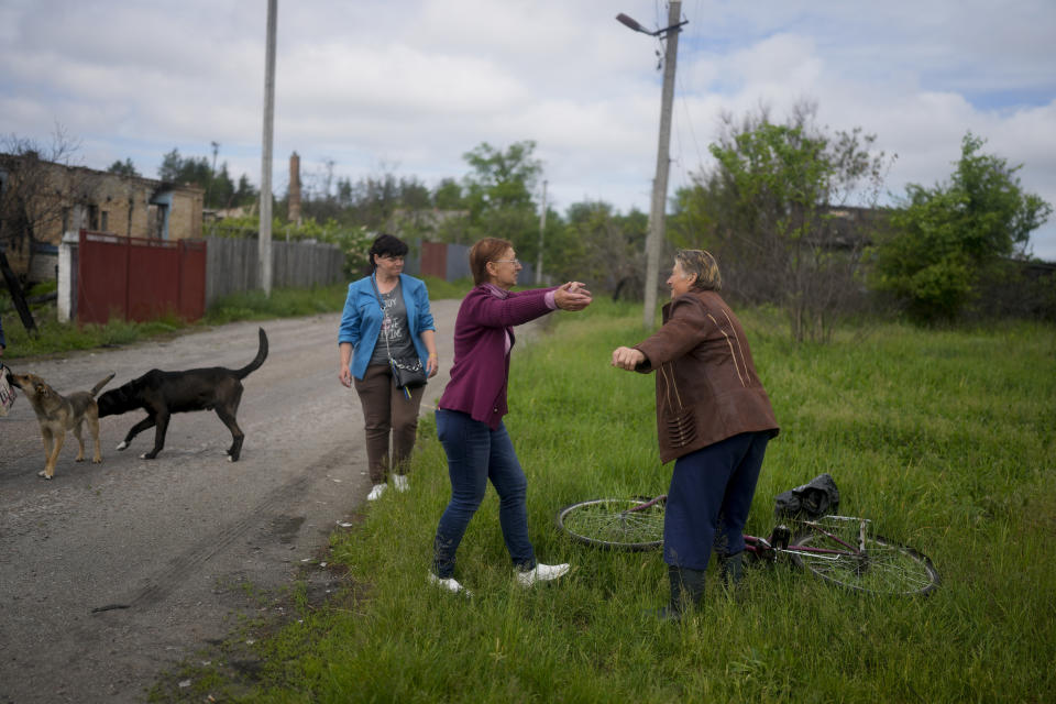 Nila Zelinska, center, is about to embrace her neighbor as she arrives to her home that was destroyed during attacks, in Potashnya, on the outskirts of Kyiv, Ukraine, Tuesday, May 31, 2022. (AP Photo/Natacha Pisarenko)