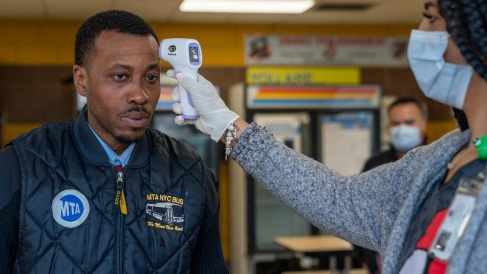 MTA bus driver John Tolbert has his temperature taken before starting his shift at the West Farms Bus Depot last April in New York City. (Photo by David Dee Delgado/Getty Images)