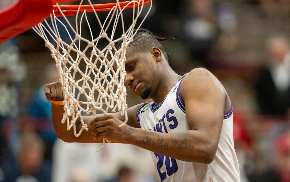 Ben Davis High School senior Ramone Enis (20) cuts down a piece of the net after an IHSAA Class 4A Boys Regional basketball game against New Palestine High School, Saturday, March 9, 2024, at Southport High School. Ben Davis won, 70-59.