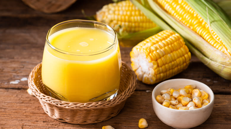 glass of corn milk in a basket with corn on the cob