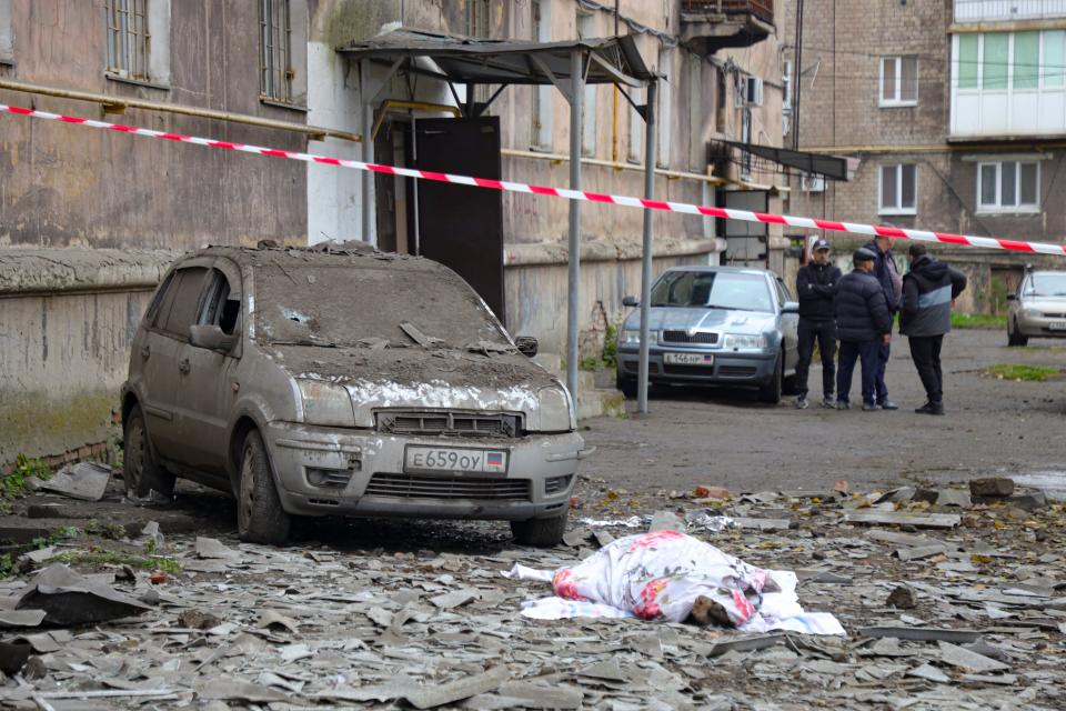 A covered lifeless body lies next to a damaged car after shelling by Ukrainian forces in Makiivka, Donetsk People's Republic, eastern Ukraine (AP)