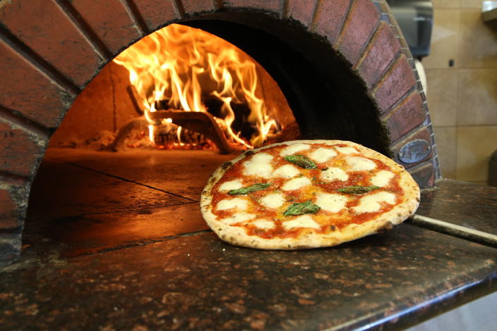 A pizza being pulled from the pizza oven