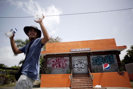 A young man offers water for sale outside a closed pizzeria in Toa Alta, Puerto Rico, June 29, 2015. REUTERS/Alvin Baez-Hernandez