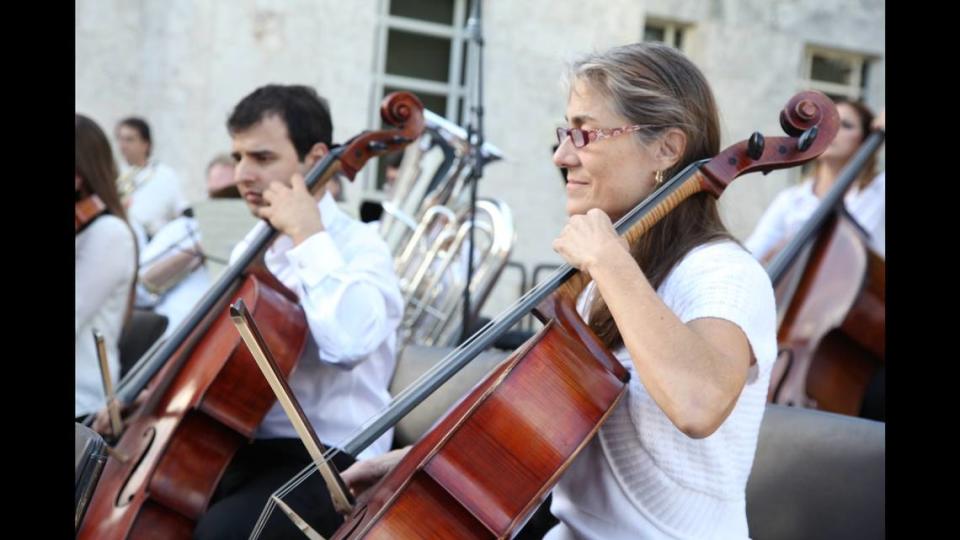 Aziz Sapaev and Barbara Corcillo play cello with Orchestra Miami at the Miami Beach 100th anniversary celebration concert in 2015.