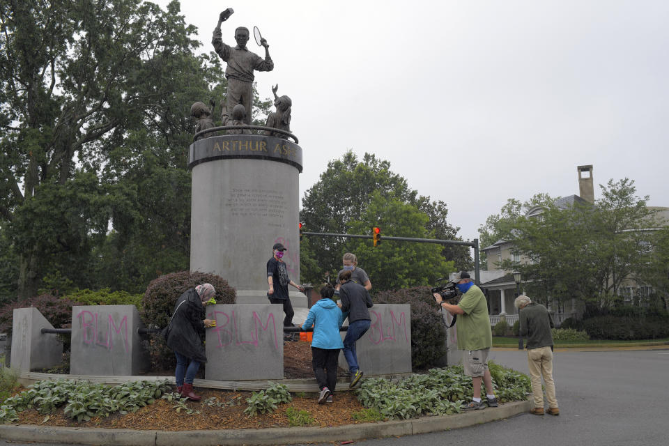 Volunteers clean off spray-painted graffiti on the Arthur Ashe memorial in Richmond, Virginia. (Photo: The Washington Post via Getty Images)