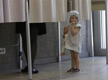 A girl holding a doll waits for her mother outside a voting booth during European Parliament and Lithuania's presidential elections in Vilnius May 25, 2014. REUTERS/Ints Kalnins