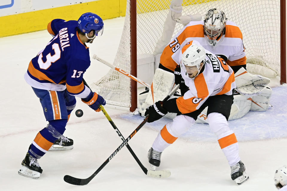 New York Islanders center Mathew Barzal (13) battles for control of the puck with Philadelphia Flyers defenseman Robert Hagg (8) as Flyers goaltender Carter Hart (79) looks on during first-period NHL Stanley Cup Eastern Conference playoff hockey game action in Toronto, Saturday, Aug. 29, 2020. (Frank Gunn/The Canadian Press via AP)