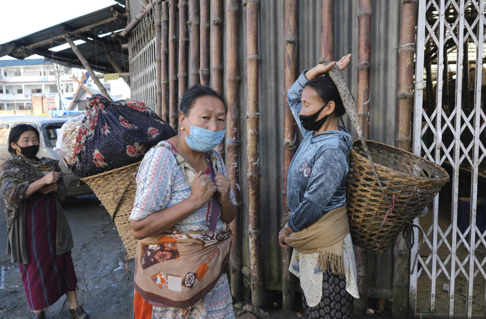 Naga women wear masks as a precaution against the coronavirus and walk past closed shops early morning in Kohima, capital of the northeastern Indian state of Nagaland, Tuesday, June 30, 2020. Several Indian states have reimposed partial or full lockdowns to stem the spread of the coronavirus. (AP Photo/Yirmiyan Arthur)