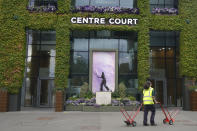 A worker passes Centre Court as preparationas take place ahead of the 2022 Wimbledon Championship at the All England Lawn Tennis and Croquet Club, Wimbledon, England, Friday, June 24, 2022. The Wimbledon Lawn Tennis Championships start on Monday, June 27, and runs for two weeks. (AP Photo/Kirsty Wigglesworth)