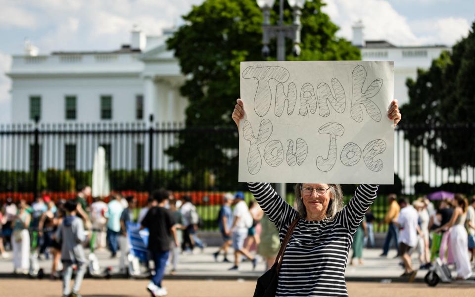 A woman holds up a banner to thank Mr Biden for standing aside