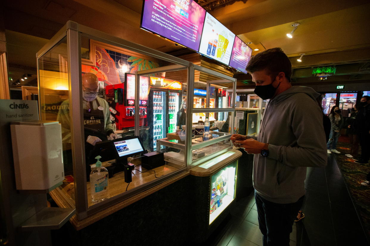 A moviegoer shops at concession stands retrofitted with plexiglass partitions before the movie 