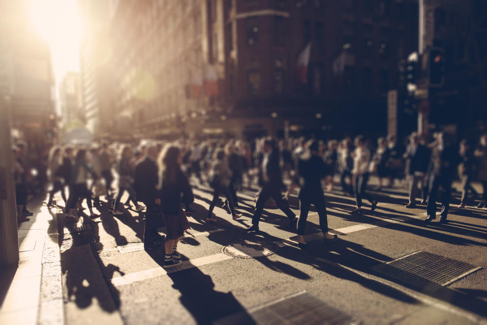 Crowd of people walking over the crosswalk at sunset. Sydney, Australia