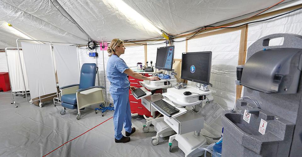 ER nurse Megan Cataldo, of Marshfield, gets a computer ready in the treatment area. South Shore Hospital ER staff is ready to treat COVID-19 patients in a tent outside the ER to prevent the possible spread to patients inside the hospital building on March 17, 2020.