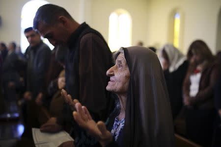 An Iraqi Christian woman prays during a mass on Christmas day at Mar Girgis Church in Baghdad, December 25, 2014. REUTERS/Ahmad Mousa/Files