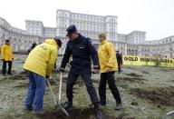 A Gendarme confiscates tools from Greenpeace activists who were digging into the yard of Romania's Parliament, to protest against a Canadian company's plan to set up Europe's biggest open-cast gold mine in Romania, in Bucharest December 9, 2013. A special Romanian parliament commission overwhelmingly rejected a draft bill that would have allowed Canada's Gabriel Resources to set up Europe's biggest open-cast gold mine in the small Carpathian town of Rosia Montana last month. However, parliament plans to revise a mining law that could open way for the project. REUTERS/Bogdan Cristel (ROMANIA - Tags: ENVIRONMENT SOCIETY CIVIL UNREST BUSINESS)