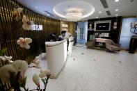 Staff members wearing face masks are seen at the reception area of the Pearl Deluxe beauty spa as the country is hit by an outbreak of the novel coronavirus, in Beijing