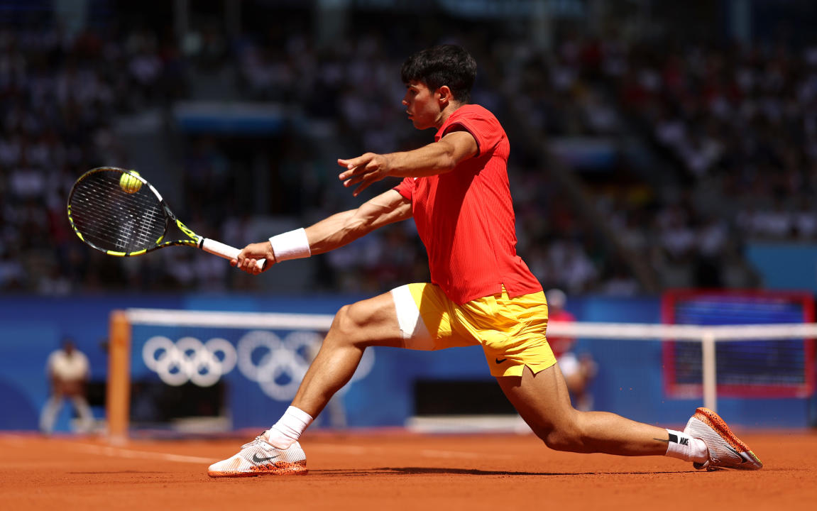 PARIS, FRANCE - AUGUST 04: Carlos Alcaraz of Team Spain stretches to play a backhand during the Men's Singles Gold medal match against Novak Djokovic of Team Serbia on day nine of the Olympic Games Paris 2024 at Roland Garros on August 04, 2024 in Paris, France. (Photo by Clive Brunskill/Getty Images)