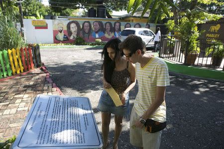 Tourists view a plaque dedicated to Bob Marley outside the Bob Marley Museum in Kingston, December 13, 2013. REUTERS/Gilbert Bellamy