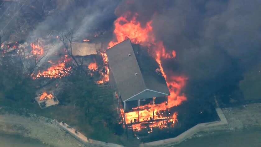 En esta imagen tomada de un video, una estructura arde durante un incendio forestal el lunes 18 de julio de 2022 en el condado de Palo Pinto, Texas. (KDFW FOX 4 vía AP)