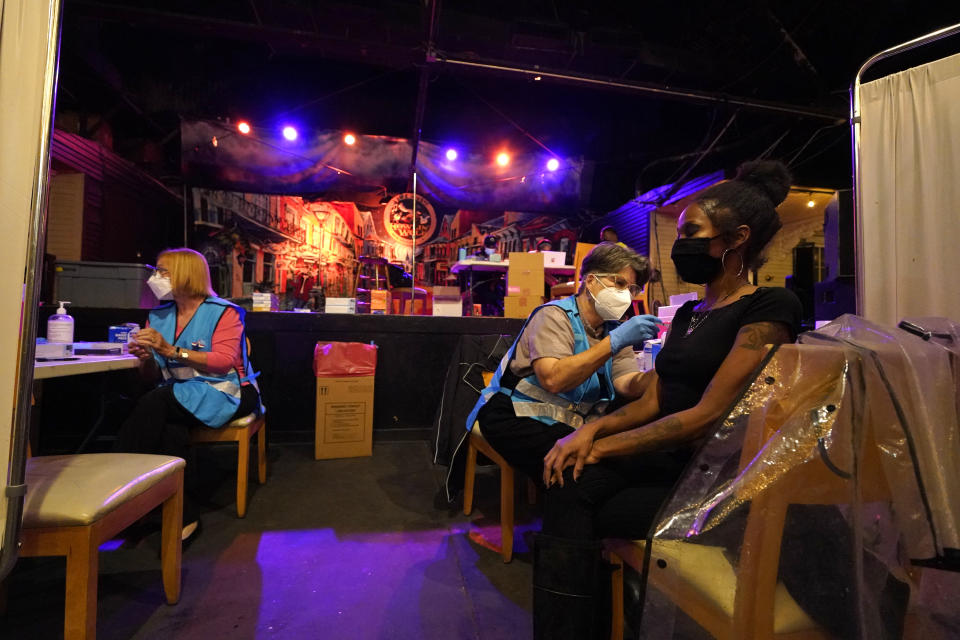 Lary Dolley receives the Moderna COVID-19 vaccine from volunteer RN Jeanne Dumestre, during a vaccine event hosted by Nola Ready, where people received a free drink at the bar if they received a COVID-19 vaccine, at The Howling Wolf, a music venue and bar, in New Orleans, Tuesday, April 13, 2021. Louisiana is making a full-court press to get shots in arms, with sometimes creative outreach to make it as easy as possible to get vaccinated. (AP Photo/Gerald Herbert)