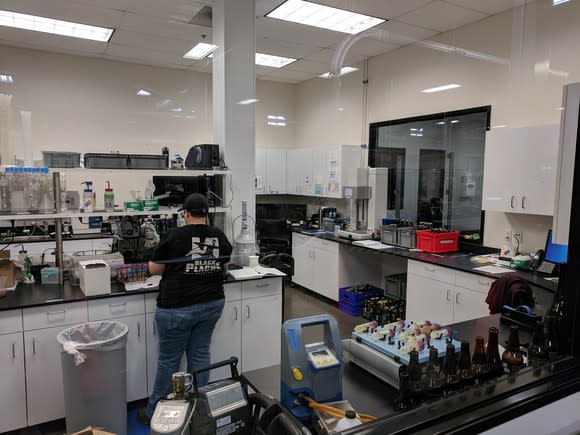 The Stone Brewing lab. A worker stands over lab equipment, testing the quality of beer as it exits production.