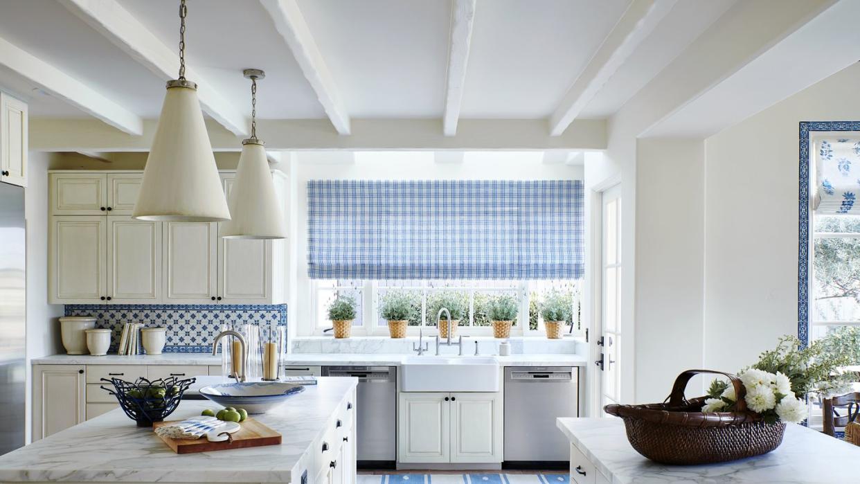 an off white kitchen with blue and white backsplash and rug and window treatment