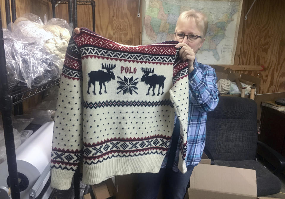 This Oct. 16, 2018 photo shows Debbie McDermott holding up the front side of a Ralph Lauren sweater in East Jordan, Mich., that athletes wore for the 2014 Winter Olympics closing ceremony. The sweater was made using Shepherd's Wool, one of Stonehedge Fiber Mill's yarn lines. (Shireen Korkzan via AP)
