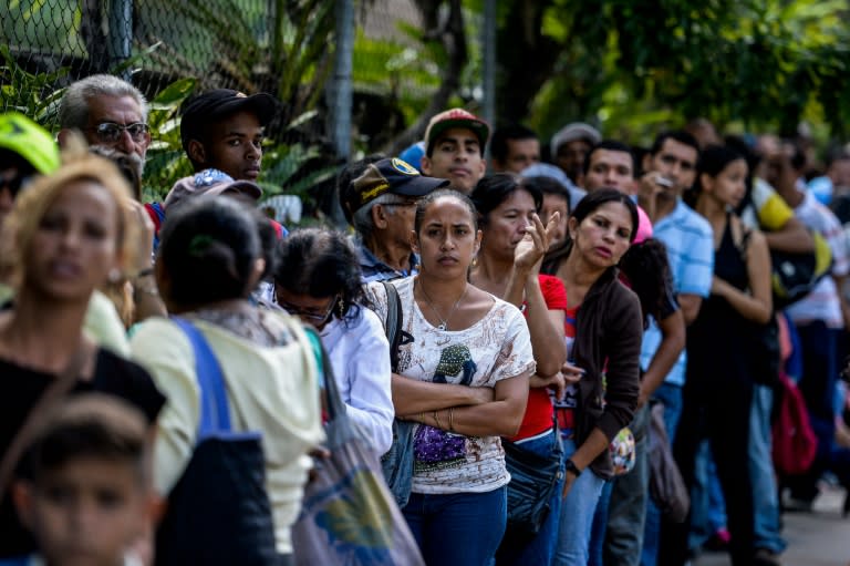 People queue to buy basic food and household items outside a supermarket in Caracas, on September 28, 2016