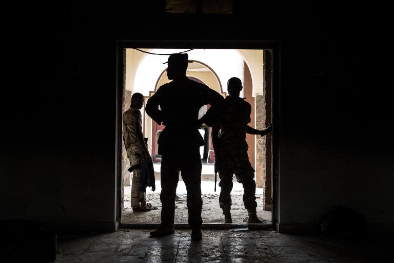 Nigerian troops inspect the former emir's palace in Bama that was used by Boko Haram as their headquarters but was burnt down when they fled, March 25, 2015