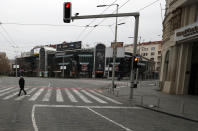 In this March 26, 2020, photo, a man walks on an empty main square during a curfew set up to help prevent the spread of the new coronavirus in Belgrade, Serbia. Since declaring nationwide state of emergency Serbian President Aleksandar Vucic has suspended parliament, giving him widespread powers such as closing borders and introducing a 12-hour curfew. (AP Photo/Darko Vojinovic)