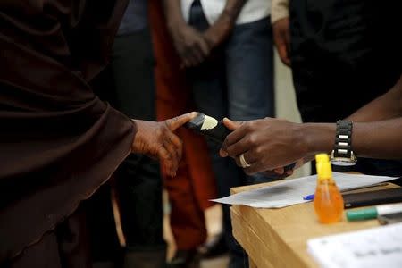 An electoral officer scans the thumb print of a voter with a reader at a polling unit at the start of general elections in Daura, northwest Nigeria, March 28, 2015. REUTERS/Akintunde Akinleye