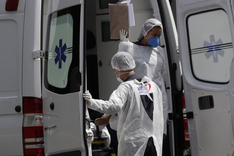 FILE - In this April 14, 2021, file photo, healthcare workers exit an ambulance carrying a patient suspected of having COVID-19 as they arrive at the HRAN public hospital in Brasilia, Brazil. The picture is still grim in parts of Europe and Asia as variants of the virus fuel an increase in new cases and the worldwide death toll closes in on 3 million.(AP Photo/Eraldo Peres, File)