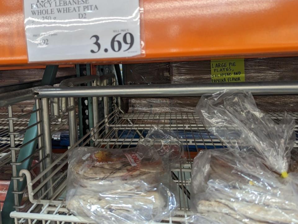 A shelf of pita bread with a sign depicting the price as $3.69