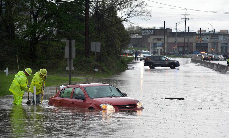 Work crew clearing drain along flooded road