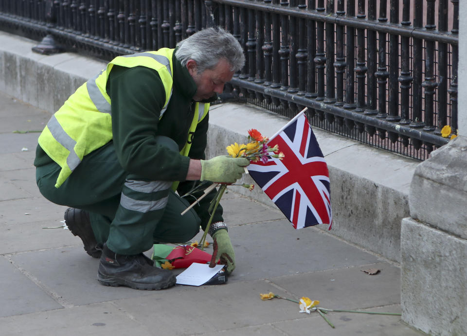 A worker clears away tributes left in honor of Britain's Prince Philip from outside Buckingham Palace in London on Saturday, April 10, 2021. Prince Philip, the irascible and tough-minded husband of Queen Elizabeth II who spent more than seven decades supporting his wife in a role that both defined and constricted his life, has died, Buckingham Palace said Friday. He was 99. (AP Photo/Tony Hicks)