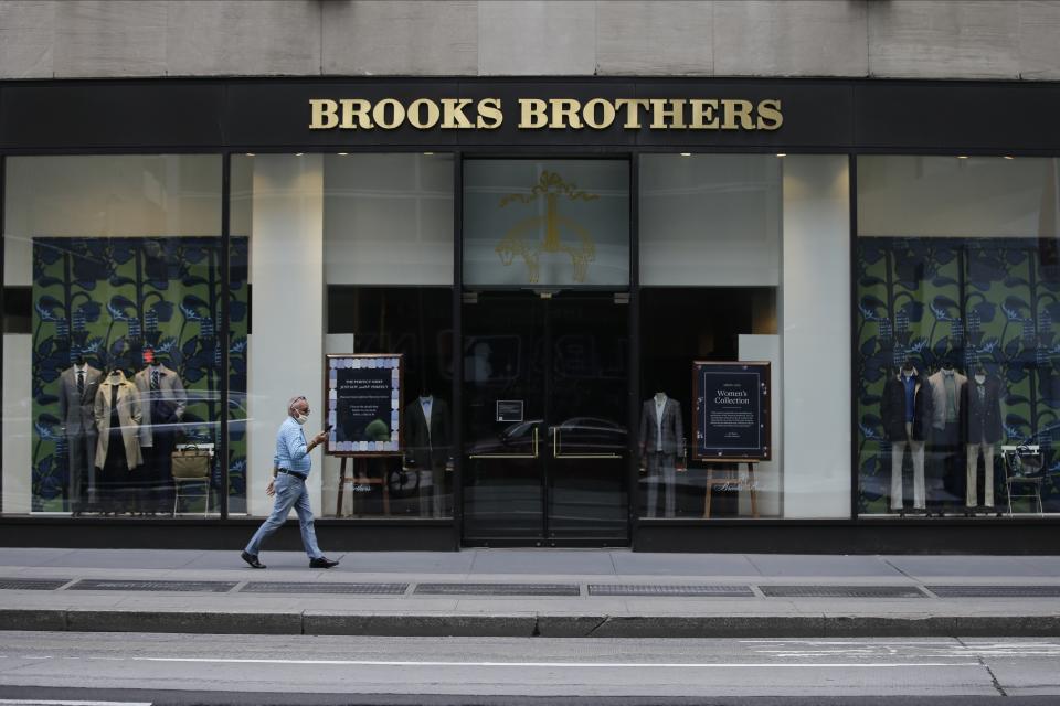 Pedestrians wearing protective masks walk past a Brooks Brothers location Wednesday, July 8, 2020, in New York. (AP Photo/Frank Franklin II)