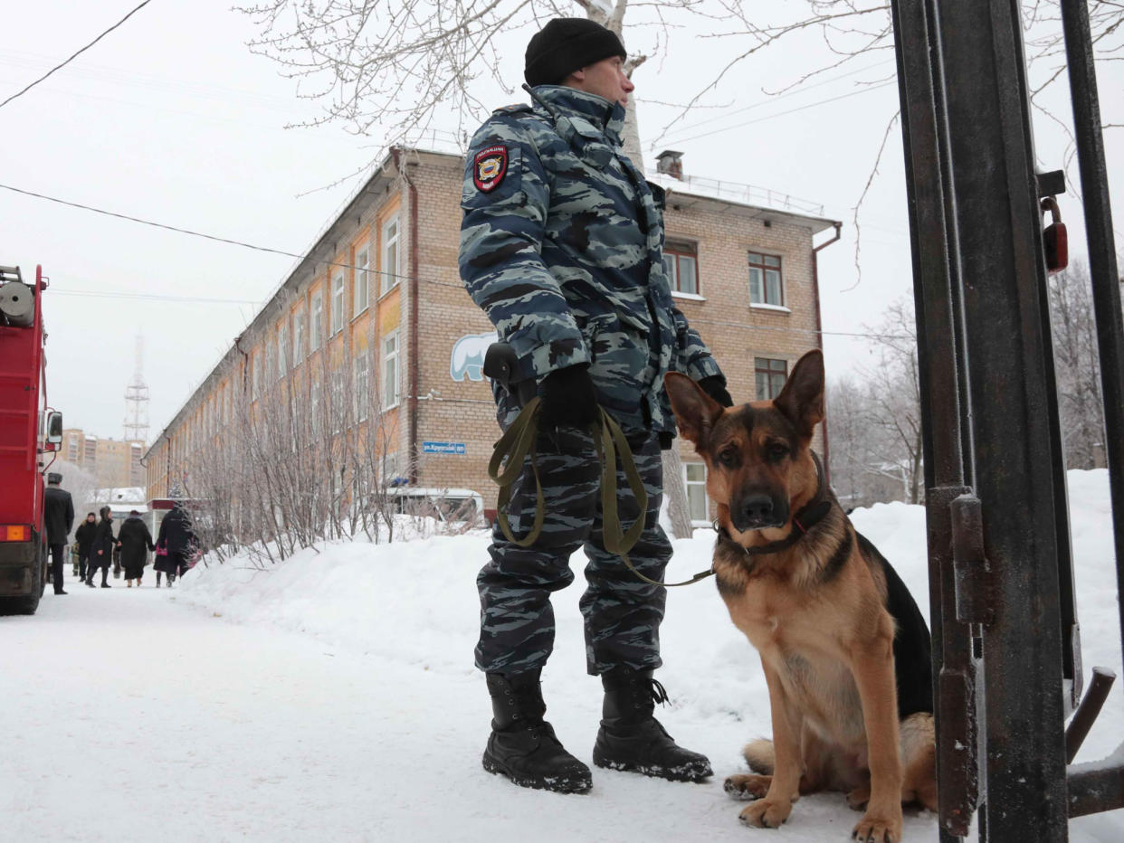 A policeman with a dog stands guard near the school after a knife fight broke out: Reuters