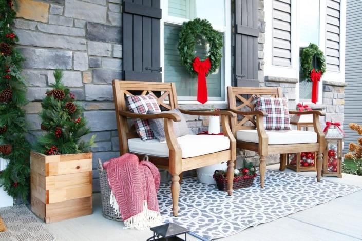 <p>Once you’ve hung your greenery, set up a seating area with a rug, wooden chairs and planters, wicker baskets, and wood lanterns. Be sure to include red blankets and pillows!</p><p><strong>Get the tutorial at </strong><a href="https://justagirlandherblog.com/traditional-christmas-porch-decor/" rel="nofollow noopener" target="_blank" data-ylk="slk:Just a Girl and Her Blog." class="link "><strong>Just a Girl and Her Blog.</strong></a></p>