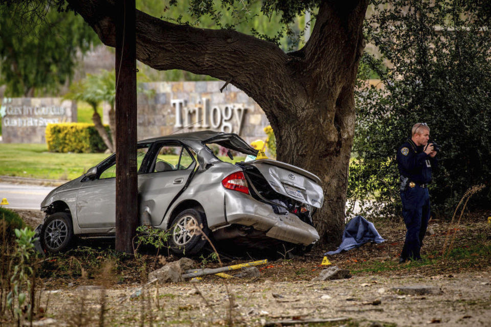 An officer with the California Highway Patrol's (CHP) Multidisciplinary Accident Investigation Team (MAIT) investigates the scene of a deadly crash in the Temescal Valley, south of Corona, Calif., Monday, Jan. 20, 2020. A Southern California driver intentionally rammed a Toyota Prius with several teenage boys inside, killing a few and injuring a few others before fleeing, authorities said Monday. (Watchara Phomicinda/The Orange County Register via AP)