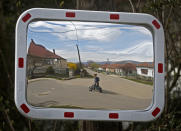 Karmen Bastyur, a 22 year old Hungarian Roma woman, is reflected in a traffic mirror carrying a bucket of drinking water from a public water pump in Bodvaszilas, Hungary, Monday, April 12,2021. TMany students from Hungary's Roma minority do not have access to computers or the internet and are struggling to keep up with online education during the pandemic. Surveys show that less than half of Roma families in Hungary have cable and mobile internet and 13% have no internet at all. (AP Photo/Laszlo Balogh)