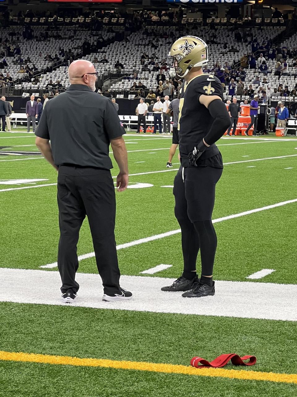 Matt Rhea, left, speaks with the New Orleans Saints Taysom Hill on the sideline during a game in New Orleans. Hill thinks of Rhea as a “mad scientist” — in a good way — while Rhea refers to himself as more of an “athlete engineer.” | Karsten Rhea