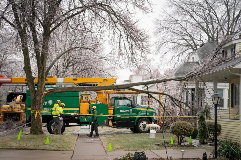 A crew from Davey Tree of Auburn Hills cuts a large tree branch back from a residential home and sidewalk on Woodward Heights blvd. in Pleasant Ridge after an ice storm in metro Detroit that causes widespread power outages, Thursday, Feb. 23, 2023.